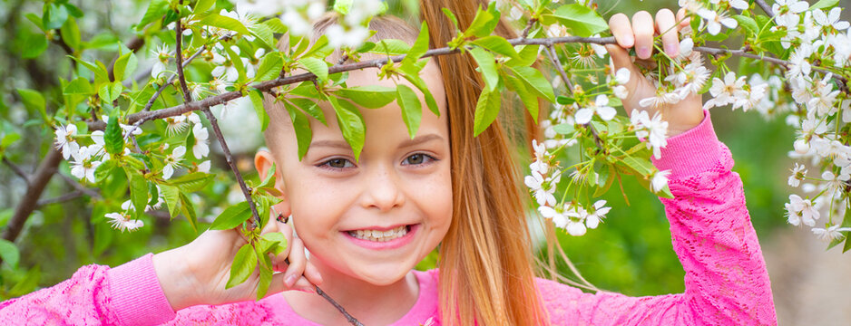 Banner with spring kids portrait. Spring teenager girl over nature green background. Kids close up face on blossom background.
