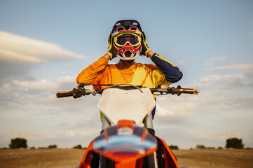 Portrait of motocross rider taking off helmet - obrazy, fototapety, plakaty
