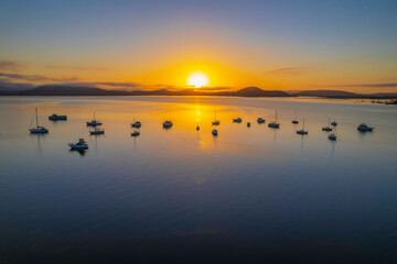 Sunrise waterscape with boats, soft clouds and reflections