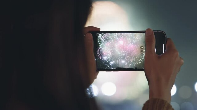 Hands of woman captures video fireworks on mobile phone.