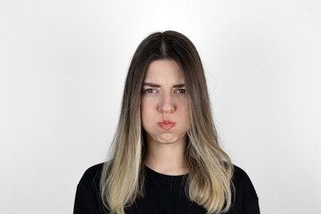 Obraz premium Close up photo of bored girl. She is blowing her cheek against white background. White background. Mouth inflated with air, crazy expression.