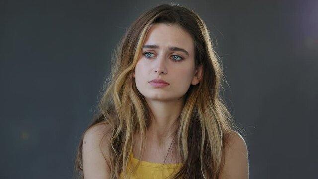 Sad offended female face, young beautiful girl lady model feels stress sadness embarrassment worries about bad news disappointed upset sorrow grief standing isolated on gray background in studio