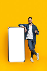 Happy arab guy leaning on huge smartphone, mockup