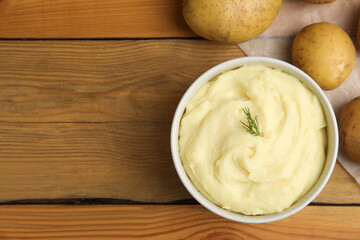 Freshly cooked homemade mashed potatoes and raw vegetables on wooden table, flat lay. Space for text