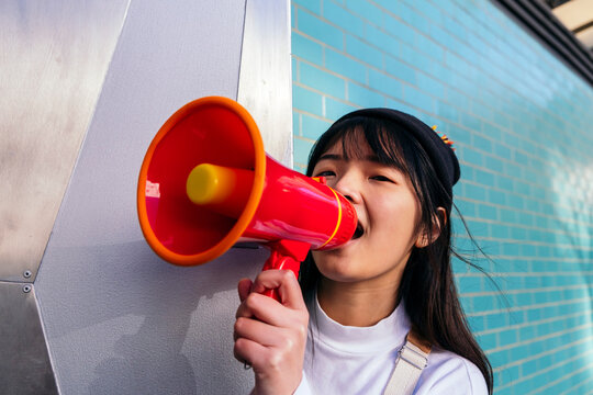 Woman shouting through megaphone from behind door