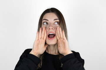 Announcing good news. Cheerful young girl holding hands around mouth and shouting while standing against white background. Crazy. 