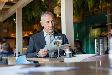 Businessman reading newspaper sitting in restaurant