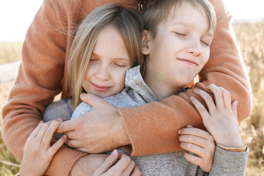 Man hugging children with eyes closed