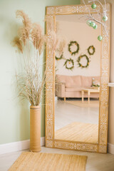 A vase with fluffy reeds, a mirror next to it. The decor of the room with your own hands. Eco-friendliness.