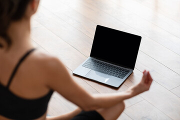 Young woman sitting in lotus position on mat with pc