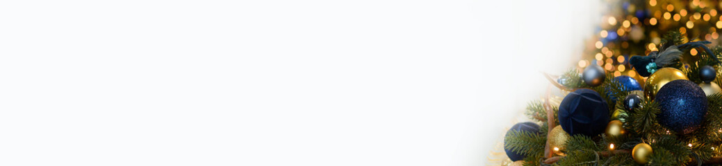 Christmas tree branch with beautiful shiny blue, gold balls and blue bird on a golden festive bokeh background. Christmas background.Banner. Copy space for text