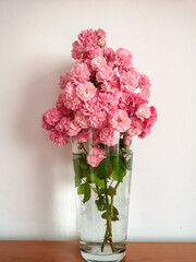 Pink rose flowers in a transparent vase, close up