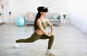 Athletic Indian lady wearing VR headset, doing virtual workout in augmented reality at home, copy...