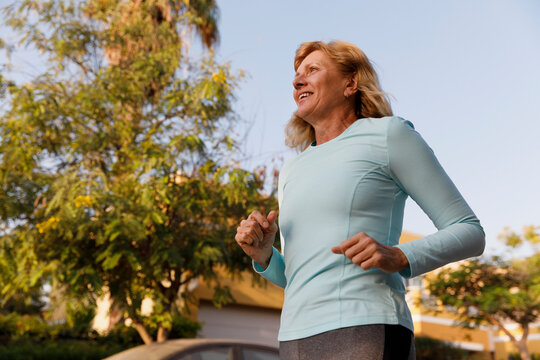 Smiling active senior woman running at park