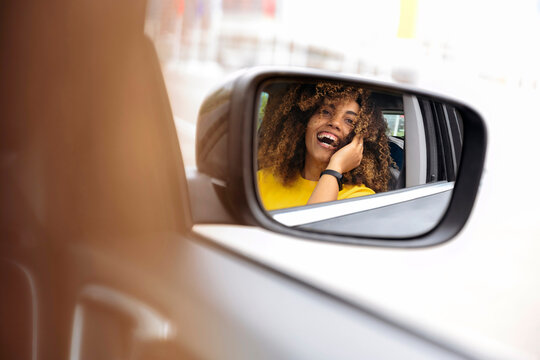Reflection of woman in side-view mirror of car