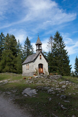 Fototapeta na wymiar Tiny church in bavaria alps, Germany with blue sky and trees in the background