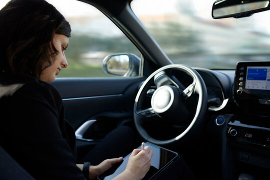 Businesswoman using tablet PC in driverless car