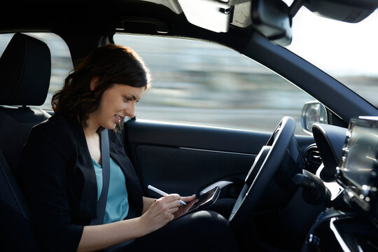 Smiling Businesswoman Using Tablet PC In Autonomous Driving Car