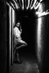 Girl in long white shirt and high heels posing in dark hallway
