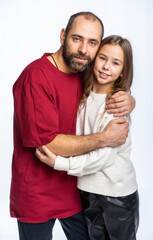 Fototapeta premium dad hugs daughter by the shoulders in the studio. a man in a burgundy-red T-shirt, a girl in a white sweatshirt. isolated white background