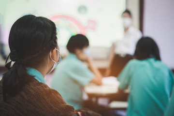 Students are studying in a classroom after lockdown with everyone wearing masks to prevent Covid-19