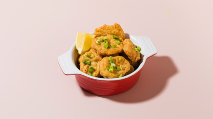 Crispy nuggets in a plate on a pink background with hard shadows. Pub menu