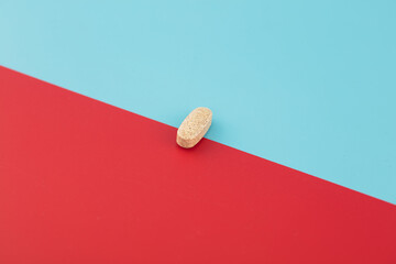 A pill is on a red and blue background