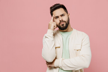 Young sad pensive thoughtful minded caucasian man 20s in trendy jacket shirt prop up head look camera forehead isolated on plain pastel light pink background studio portrait. People lifestyle concept.