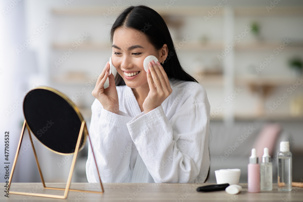 Wall mural pretty asian woman cleaning her face with toner