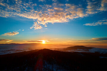Sunset over mountans covered with forest, beautiful winter landscape, nature background, aerial view
