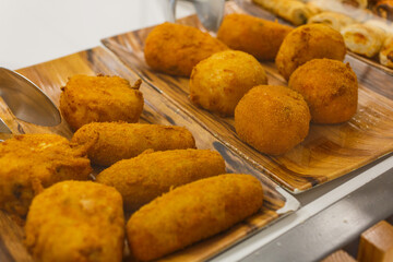 Crocchè di patate fritti, arancini di riso fritti e frittatine di pasta fritte fotografati in una vetrina di una rosticceria