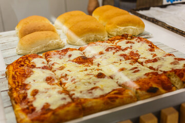 Pizza margherita con sugo di pomodoro e mozzarella fotografata in una vetrina di una rosticceria