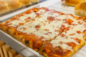 Pizza margherita con sugo di pomodoro e mozzarella fotografata in una vetrina di una rosticceria