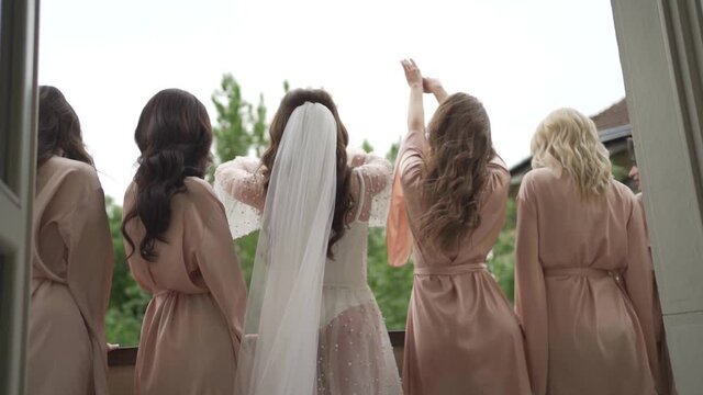 Bride and her bridesmaids are having fun on balcony. Morning meeting of the bride on the wedding party. Beautiful dresses. Slow motion.