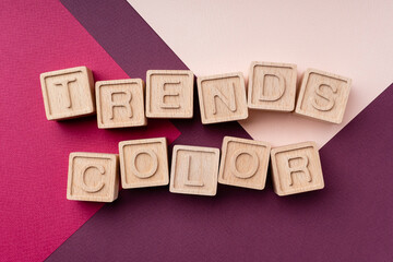 Color trends 2022, flat, lay, top view. The inscription is made of eco-friendly wooden cubes. Concept trends 2022 against the background of burgundy and Calming coral. Bright geometric background