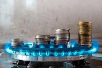 Coins pile up on a burning gas burner. The concept is to increase the cost of supply , payment for natural gas.