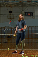 Female tennis player with racket and ball on gym background