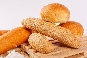 Panini appena sfornati di diverse dimensioni fotografati su un tagliere di legno e con una montagnetta di farina davanti