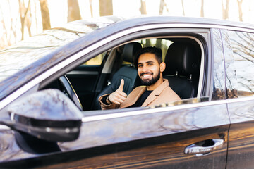 Young asian man smiling and showing thumb up in the car.