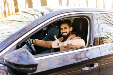 Young asian man smiling and showing thumb up in the car.