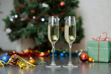 Champagne glasses and gifts, with New Year's toys near  Christmas tree decorated with colorful lights and  garland