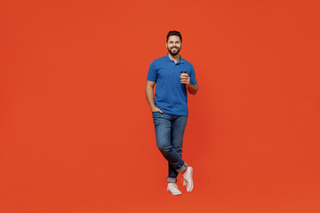 Fototapeta na wymiar Full body young smiling happy man 20s wear basic blue t-shirt looking camera hold takeaway delivery craft paper brown cup coffee to go isolated on plain orange background. People lifestyle concept