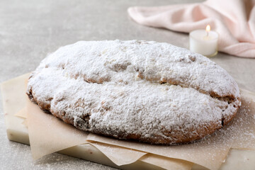 Delicious Stollen sprinkled with powdered sugar on light table, closeup