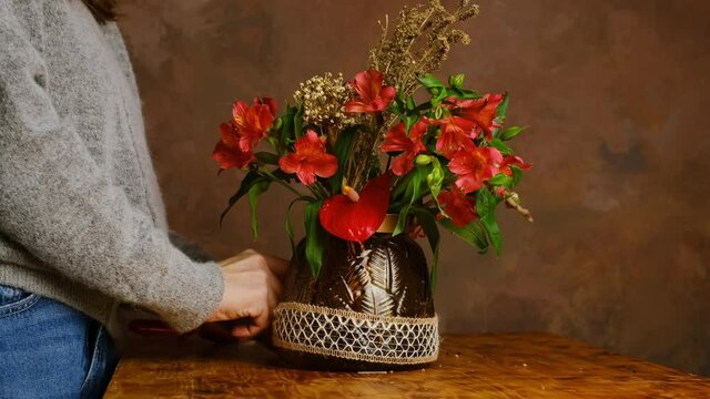 Valentines day flower arrangement, festive home decor. Young woman decorating bouquet of flowers for Valentine's day. Florist at work.