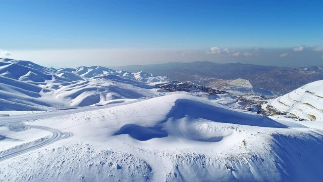 Aerial winter view with mountains covered by snow. Sunny day. Mountain peak with snow. Ski slopes
