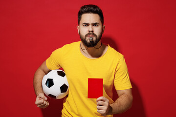 Angry irritated young bearded man football trainer in yellow t-shirt hold soccer ball whistle show...
