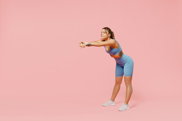 Fototapeta na wymiar Full body young strong sporty athletic fitness trainer instructor woman 20s wear blue tracksuit spend time in home gym do squats isolated on pastel plain light pink background. Workout sport concept.