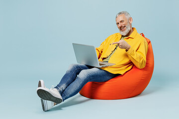 Full body smiling cool elderly gray-haired mustache bearded man 50s wear yellow shirt sit in bag...