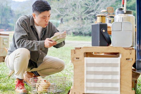 A Young Man Arranging Camping Dishes In Front Of A Camping Car