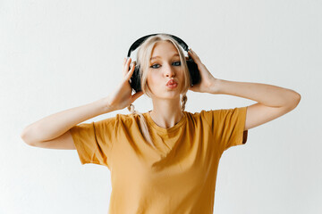 Flirty blonde woman in headphones listening to music on white background